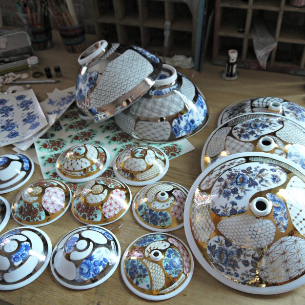 Working on some small and large budvases, salt & pepper shaker, applying decals and gold luster Working on some small and large budvases, salt & pepper shaker, applying decals and gold luster