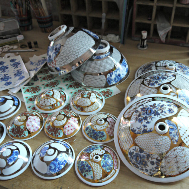 Working on some small and large budvases, salt & pepper shaker, applying decals and gold luster Working on some small and large budvases, salt & pepper shaker, applying decals and gold luster